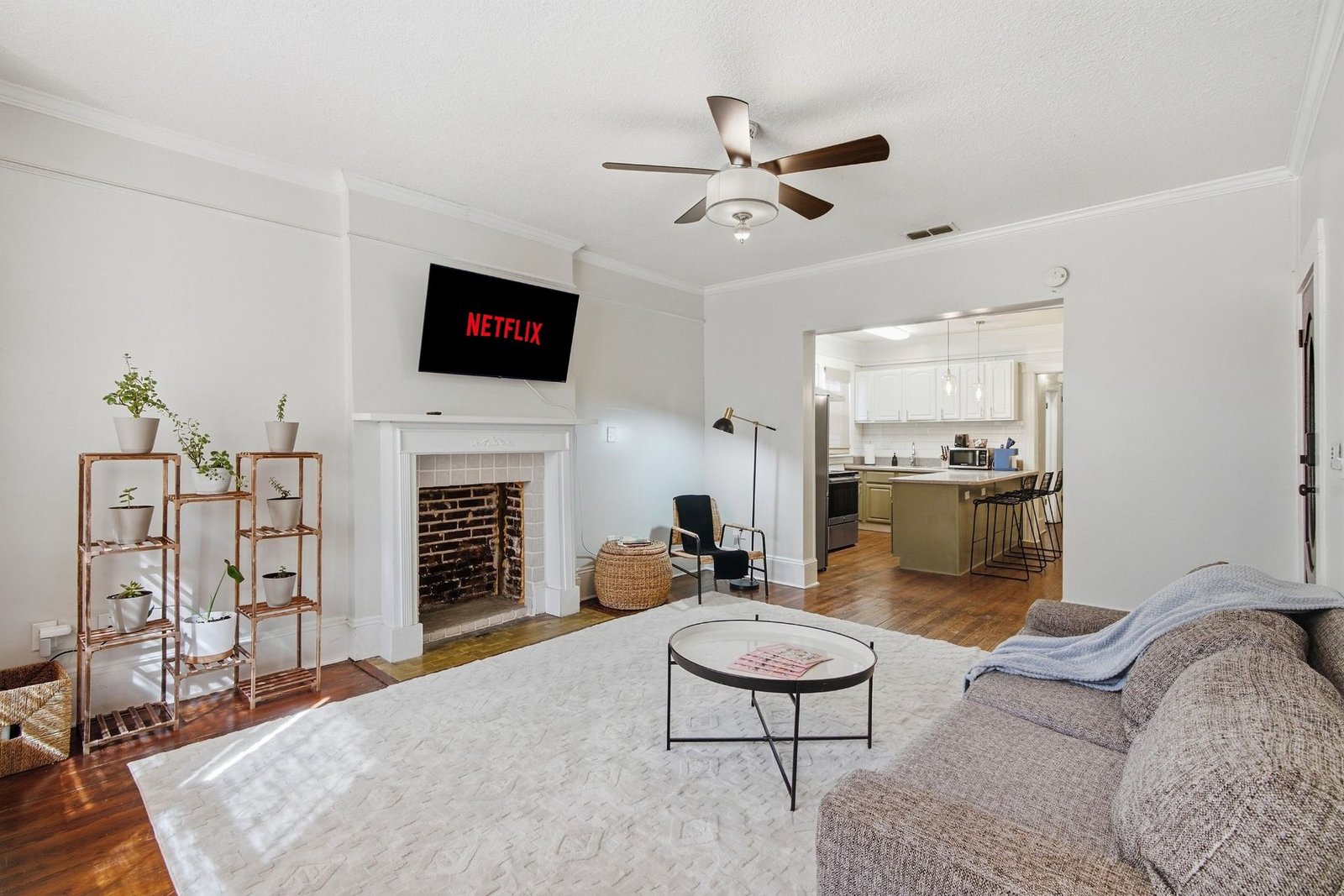 Bright open living room with fireplace and smart TV, open to the kitchen